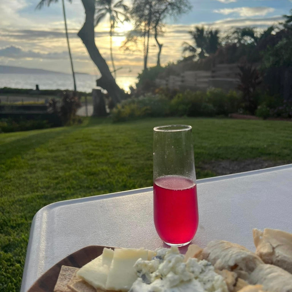 red tropical cocktail with a cheese platter on the beach